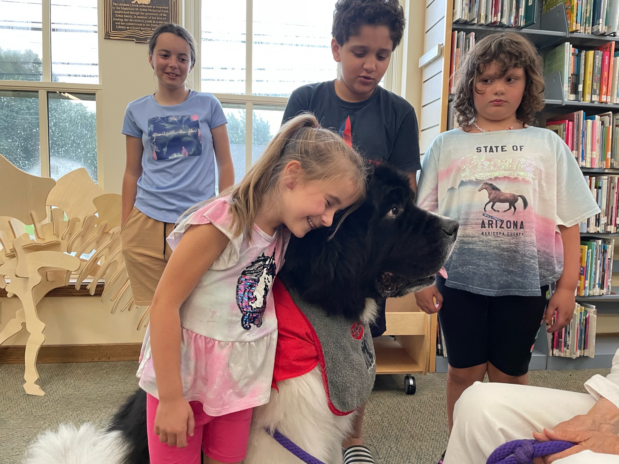 Four kids pet a big therapy dog.